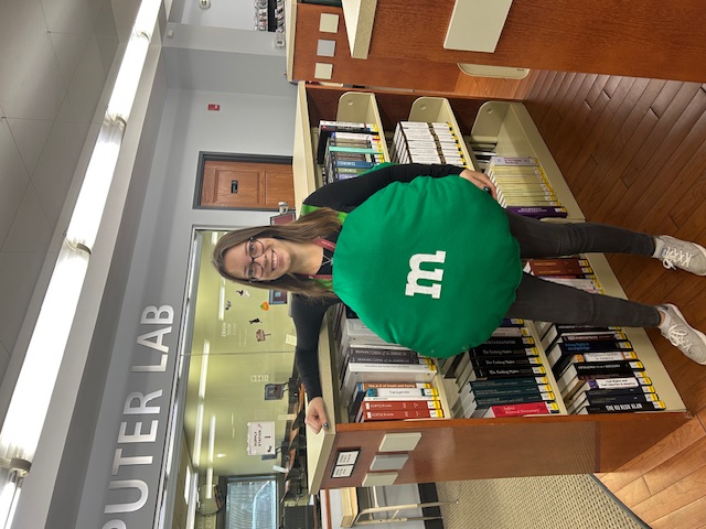 Adult Services Supervisor Chrissy, dressed up in a green M&M costume