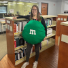 Adult Services Supervisor Chrissy, dressed up in a green M&M costume