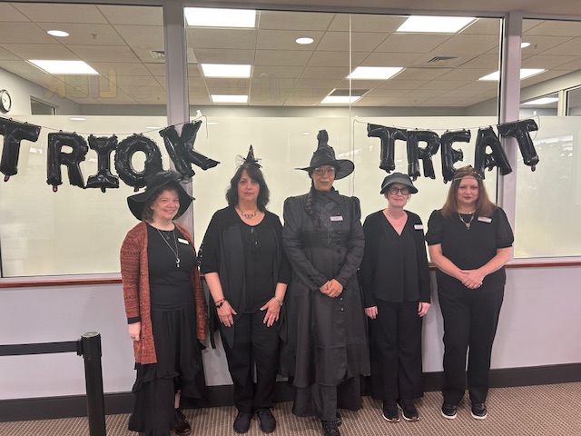 Circulation staff dressed up as witches. From left to right, library assistant Jaime, library assistant Cheryl, library assistant Bernice, circulation supervisor Laurie, and library assistant Donna