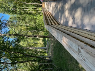 A wooden bridge suspended over green shrubbery